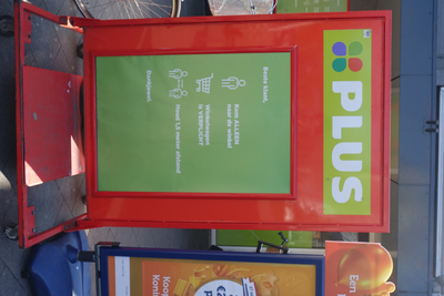 NOC-Covid-19-003 Bord bij entree van Plus supermarkt, met verzoek om afstand te houden.